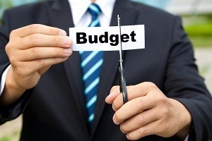 businessman with scissors cutting label Budget